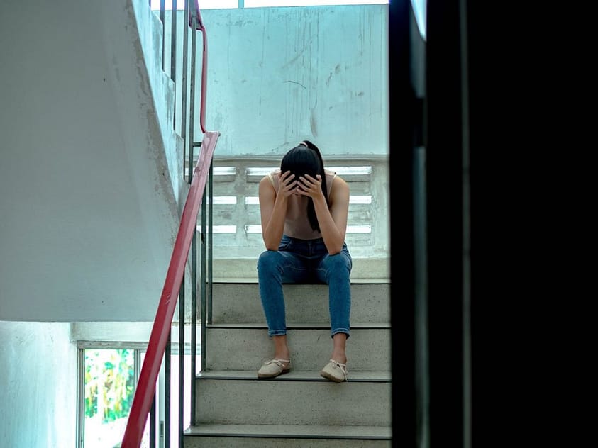 A young woman deals with addiction and loneliness on the stairs.