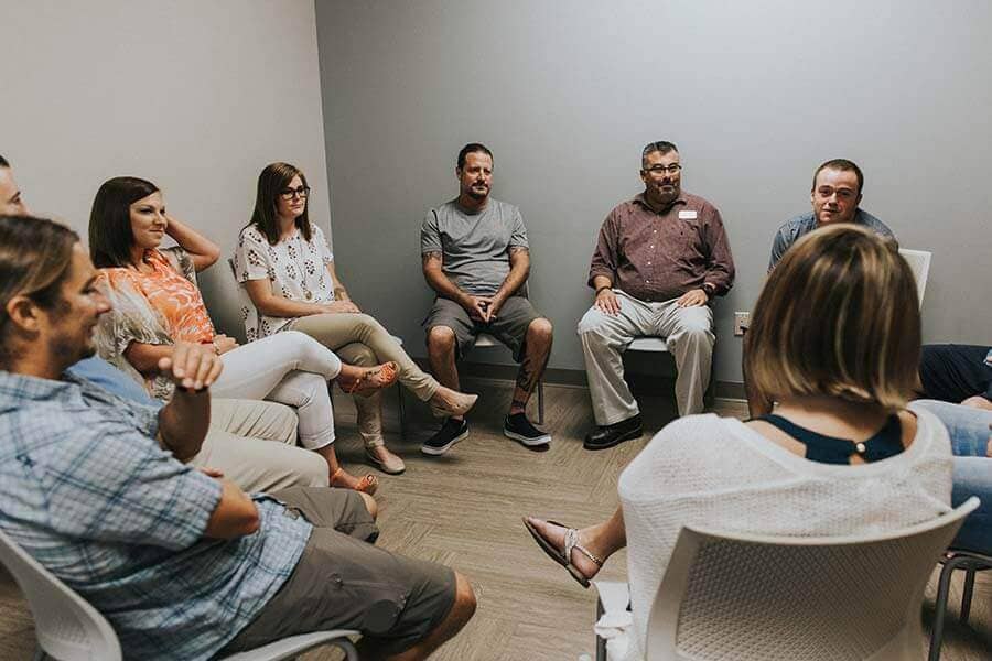 Many patients sitting in a circle for a drug rehab group therapy session