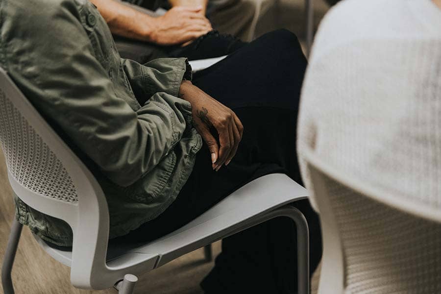 Man with spider tattoo sitting in a drug rehab group therapy session