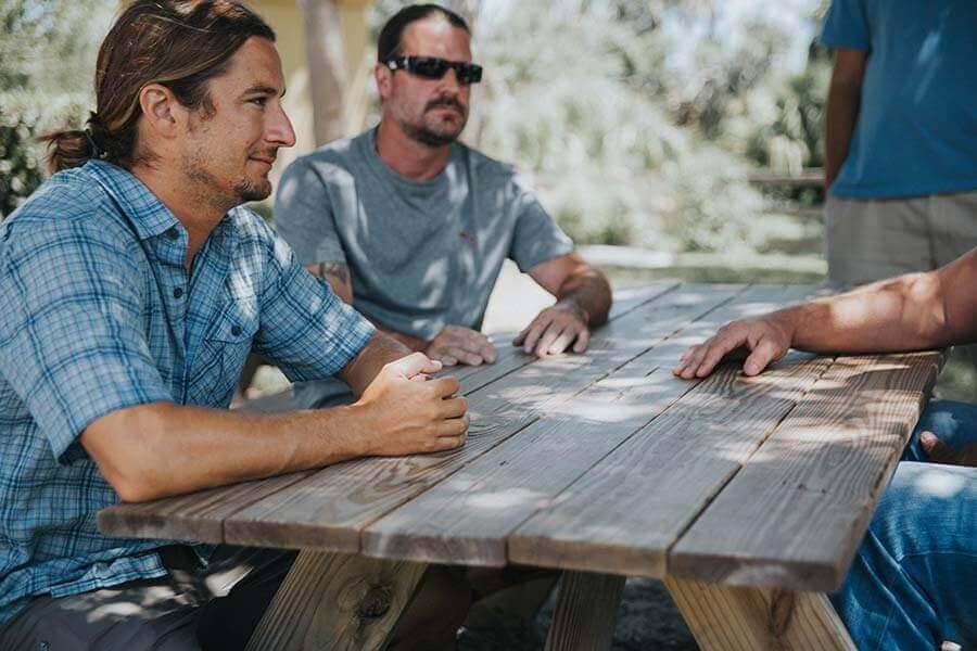 Three male patients speaking at a picnic table