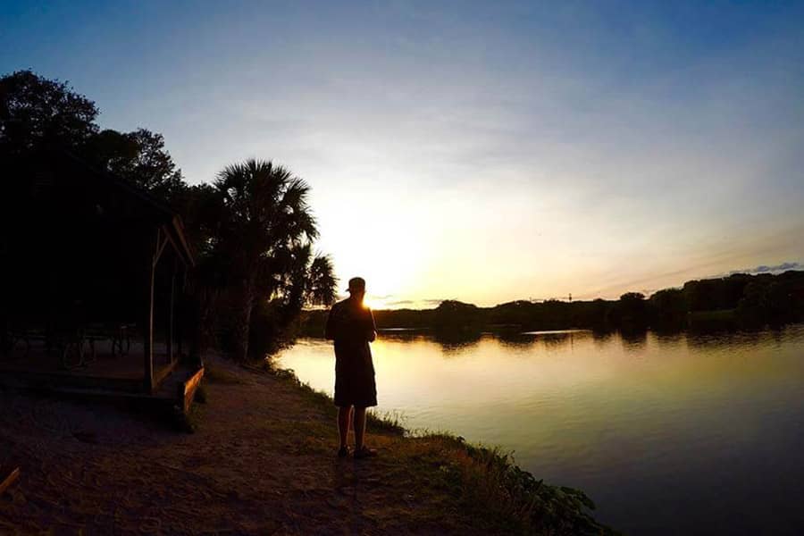 Man standing by a lake at sunset