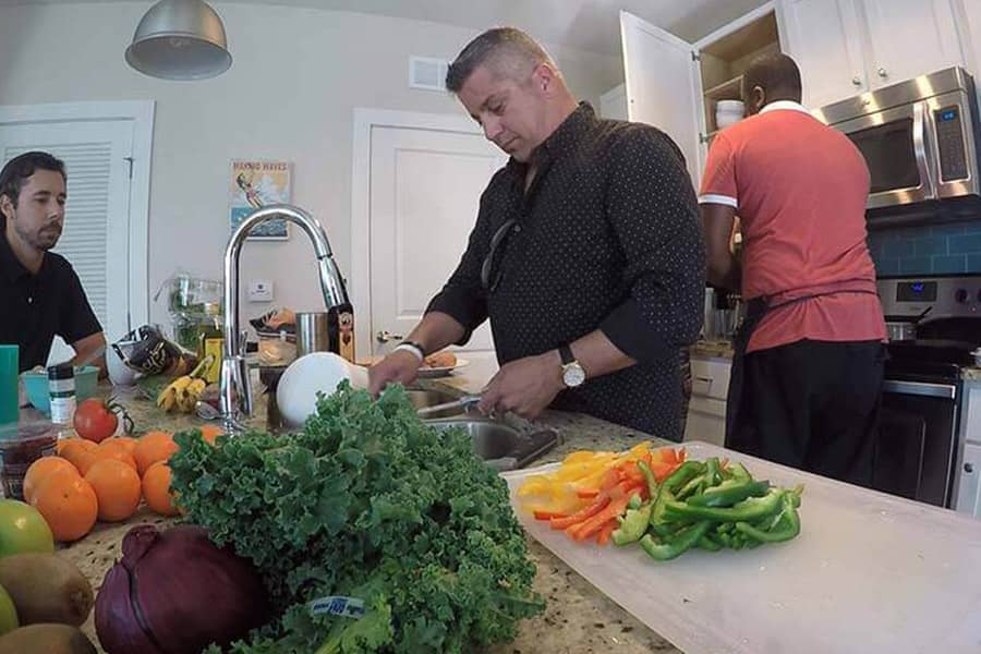 Male patients in a drug rehab house preparing vegetables for dinner