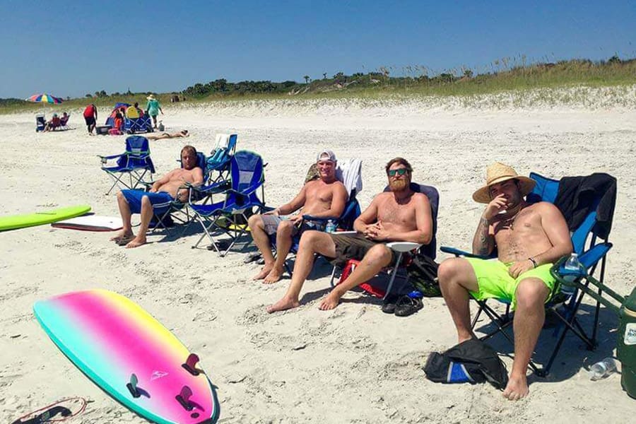 Four men sitting in chairs on the beach